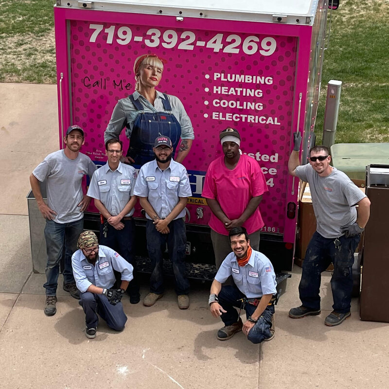 The Smith Total Home team of technicians in Colorado Springs in front of a Smith pink service truck
